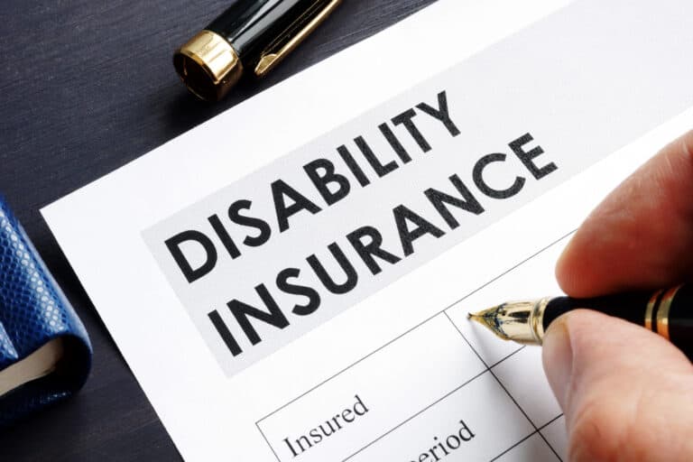 Close-up of a hand filling in a form labeled Disability Insurance; weighing private disability vs. Social Security benefits.