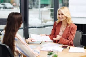 Disabled job candidate passing an interviewer her résumé in an office setting; following working while on LTD rules.