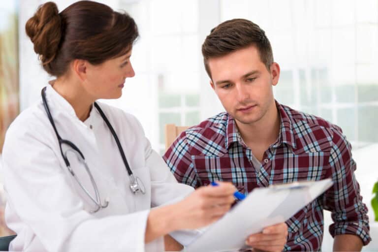 Patient reviewing chart with a physician wearing white lab coat and stethoscope; medical conditions that qualify for long-term disability.