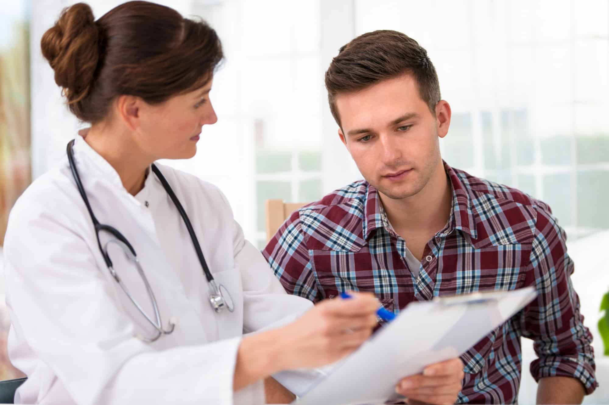 Patient reviewing chart with a physician wearing white lab coat and stethoscope; medical conditions that qualify for long-term disability.