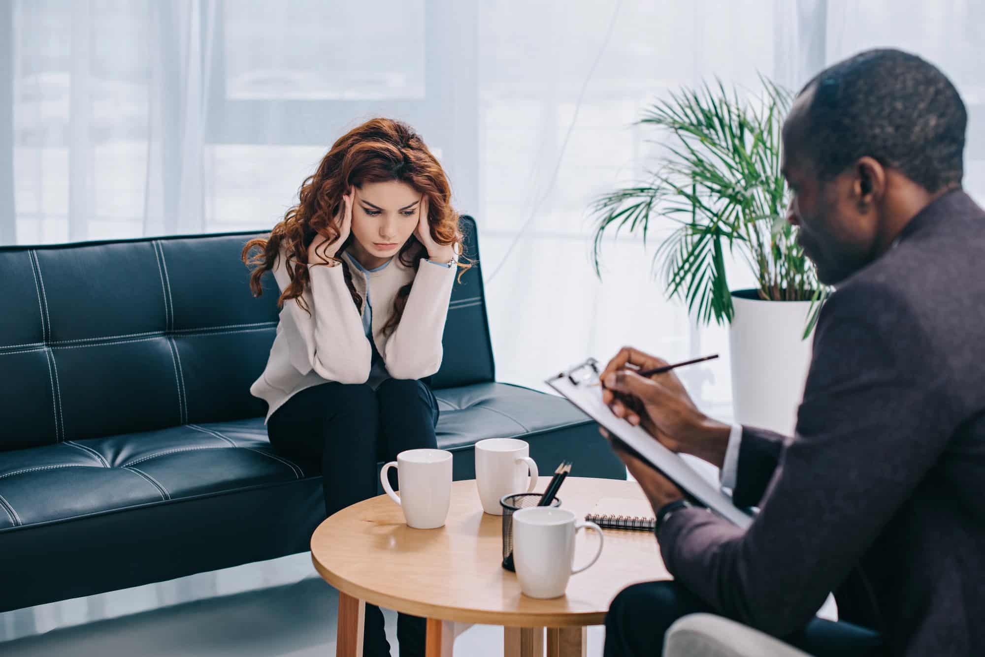 Young woman on sofa in psychiatrist’s office, undergoing mental health assessment; establishing mental health qualifications for LTD.