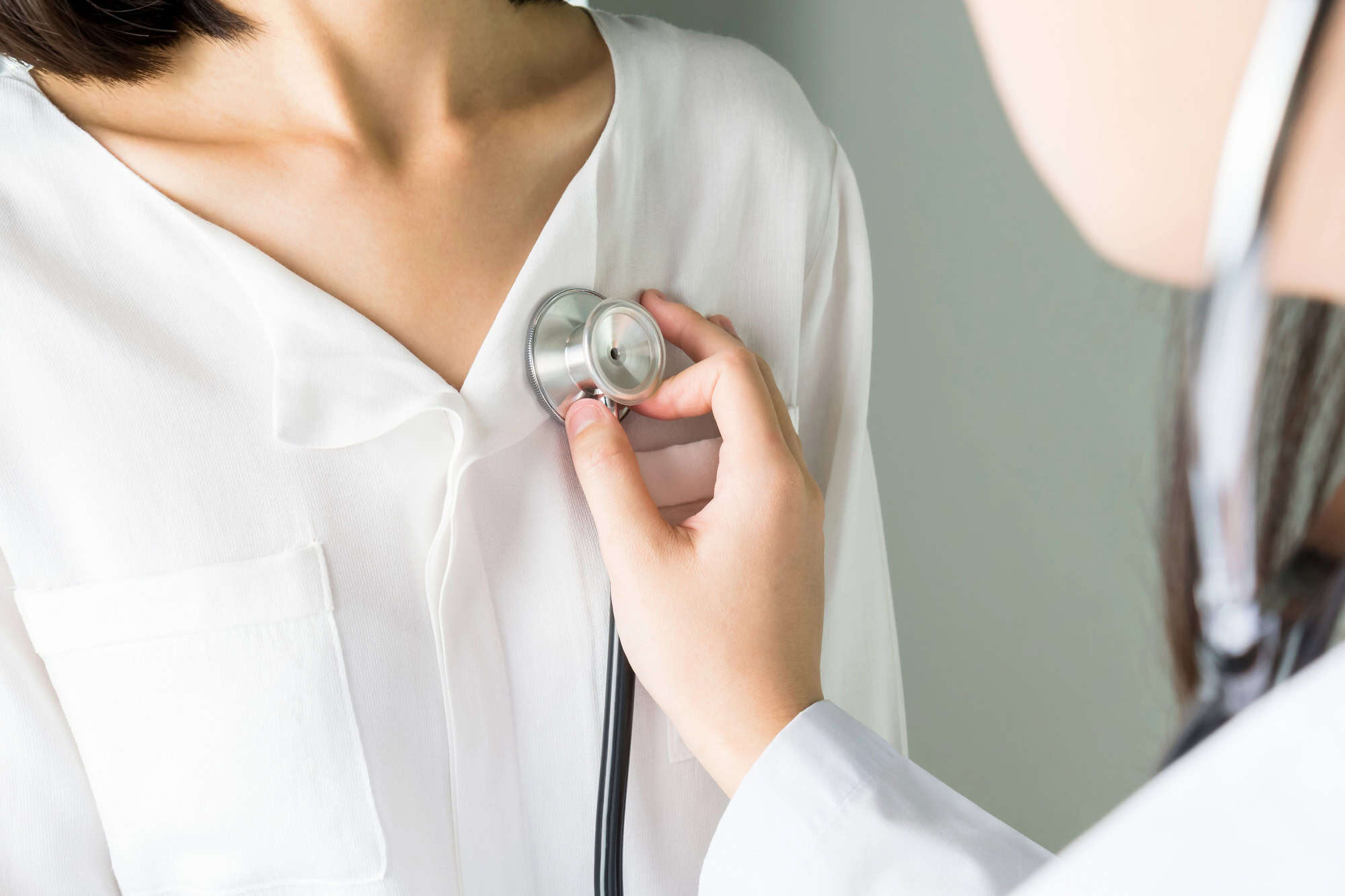 A physician listening to a patient’s chest through a stethoscope during a doctor visit for long-term disability claim.
