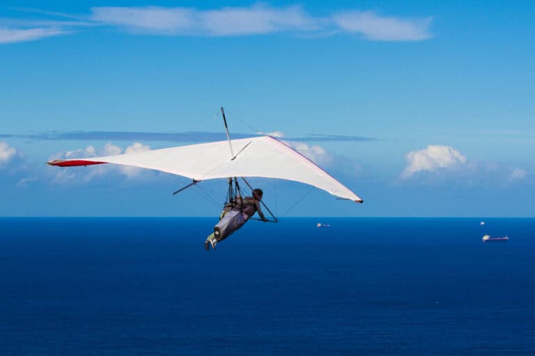 Man hang-gliding over a calm ocean on a sunny day; lifestyle choices’ effect on LTD eligibility.