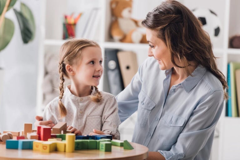 A mother sitting with her arm around a small child in front of a table covered in toy blocks; planning for LTD benefits in child support determinations.