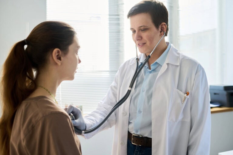 A healthcare professional listening to a patient’s chest through a stethoscope; healthcare professionals’ role in LTD claims.